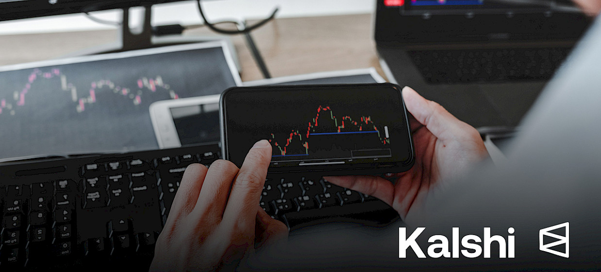Hands hold a smartphone showing a market chart; Kalshi and Polymarket logos.